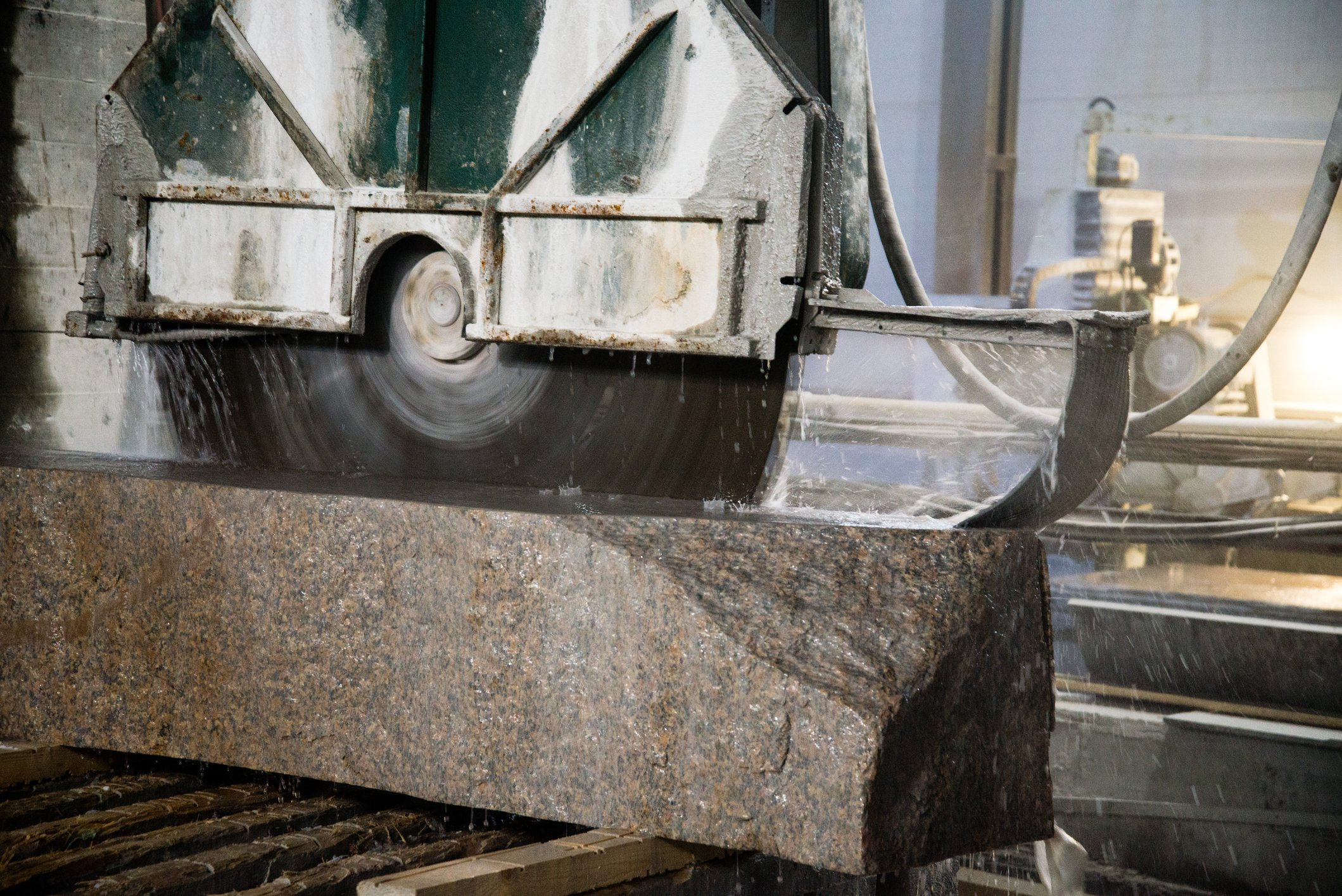 Granite processing in manufacturing. Cutting granite slab with a circular saw.